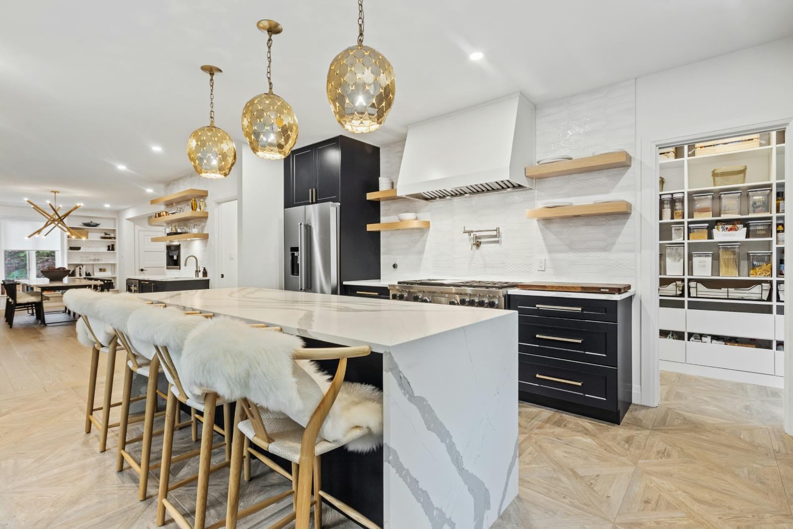 Kitchen island with white waterfall countertop and brass pendant lighting